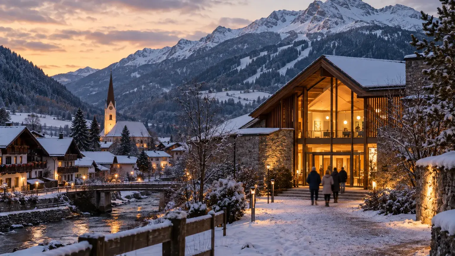 Dorf im Ennstal am frühen Winterabend, leichter Schnee, warm beleuchtetes Kulturhaus und kleine Gestalten von hinten
